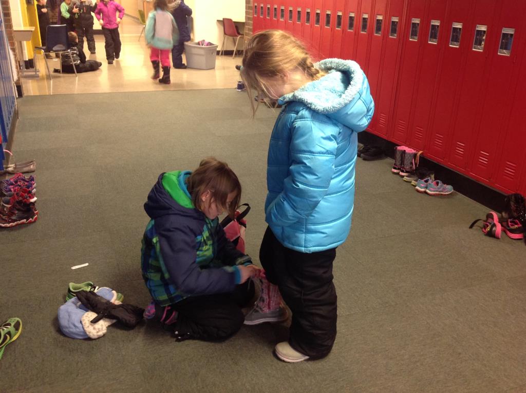 Student assisting another student with her boots.